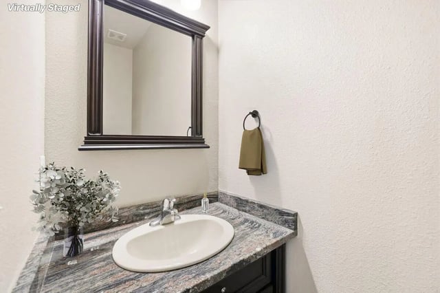 Sink mirror towel rack and flowers bathroom at Stadium Properties Apartments in Tallahassee Student Accommodation