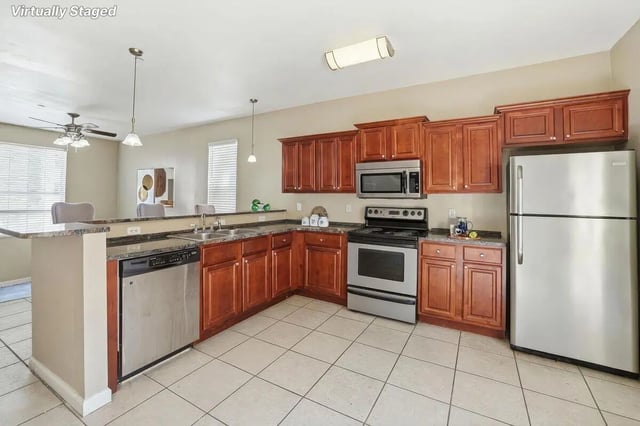 Wood cabinets stainless steel appliances countertops and tiled floor kitchen at Stadium Properties Apartments in Tallahassee Student Accommodation