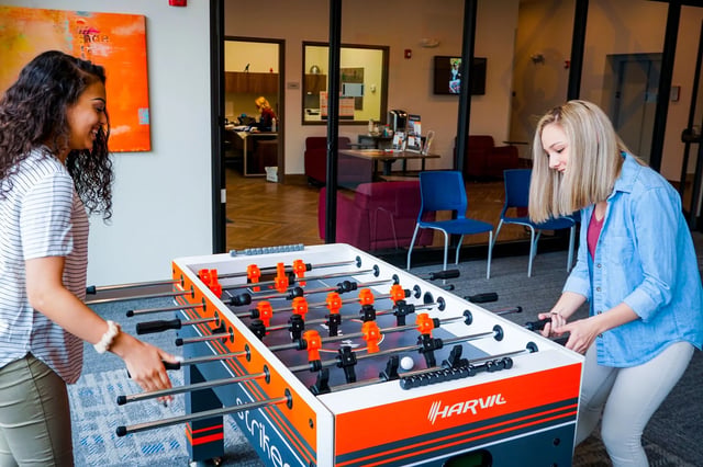 Women playing foosball table in common area living room at Highland Quarters in Terre Haute Student Accommodation