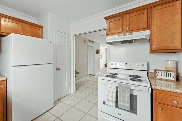 White refrigerator wooden cabinets white stove kitchen at Villa Capri Apartments in Tallahassee Student Accommodation