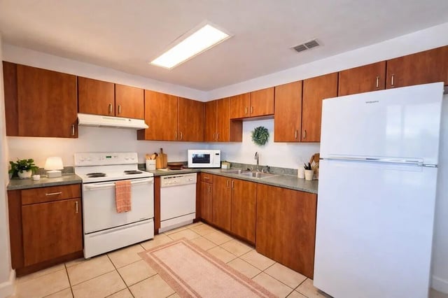Wood cabinets white appliances sink and refrigerator kitchen at Villa Cristina in Tallahassee Student Accommodation
