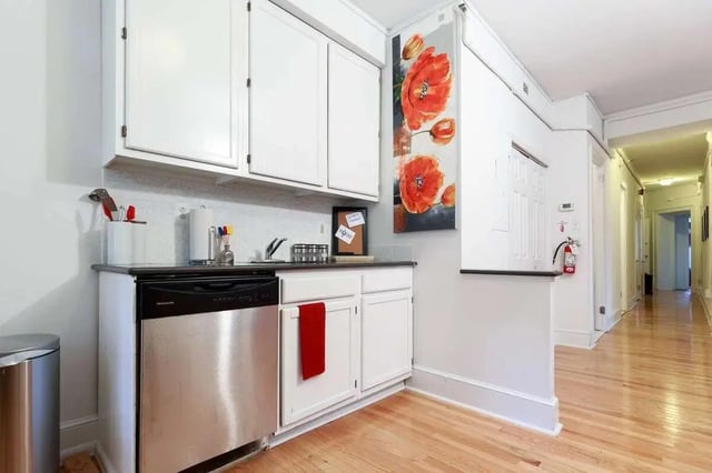 White cabinets dishwasher artwork hallway kitchen at The Legacy at Drexel Arms Apartments in Philadelphia Student Accommodation