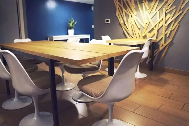 Wooden table white chairs plant wall art dining area at The Legacy at Drexel Arms Apartments in Philadelphia Student Accommodation