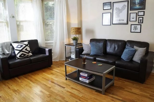 Black leather sofas coffee table and artwork Living room at The Legacy at Drexel Arms Apartments in Philadelphia Student Accommodation