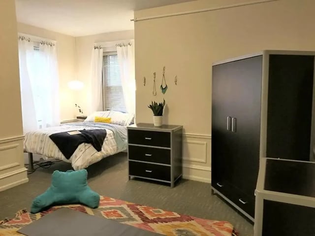Bed dresser wardrobe and rug bedroom at The Legacy at Drexel Arms Apartments in Philadelphia Student Accommodation