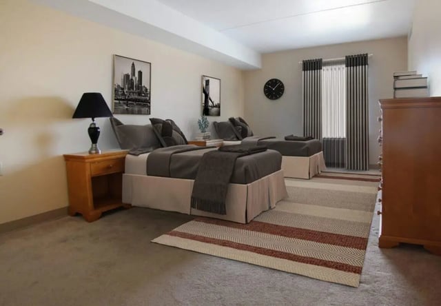 Two beds bedside table dresser rug bedroom at Palmerton Apartment Complex in State College Student Accommodation