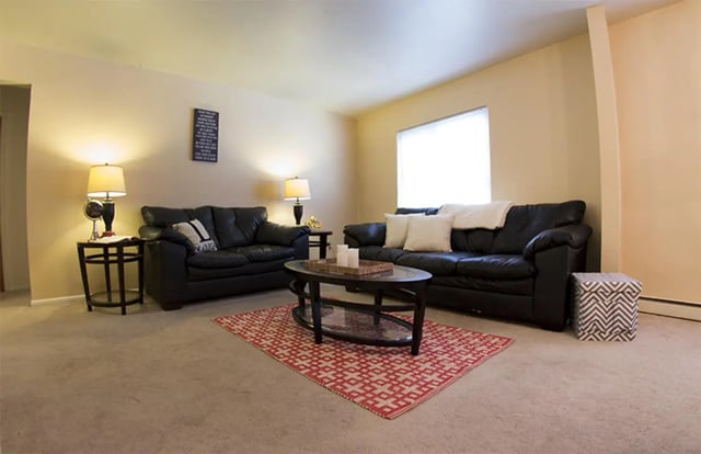 Two black sofas coffee table ottoman living room at Sutton Court in State College Student Accommodation