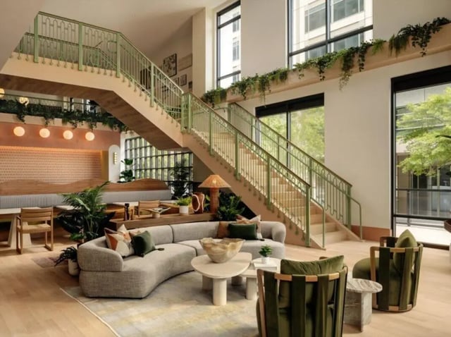 Curved sofa green chairs stairs plants living room at Rambler Atlanta Apartments in Atlanta Student Accommodation