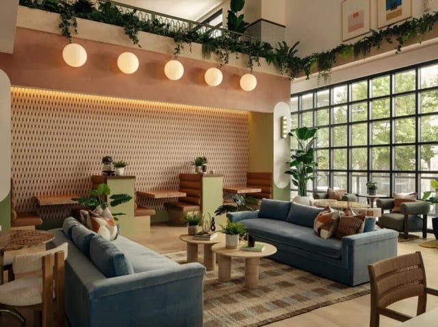 Blue sofas coffee tables plants patterned wall living room at Rambler Atlanta Apartments in Atlanta Student Accommodation