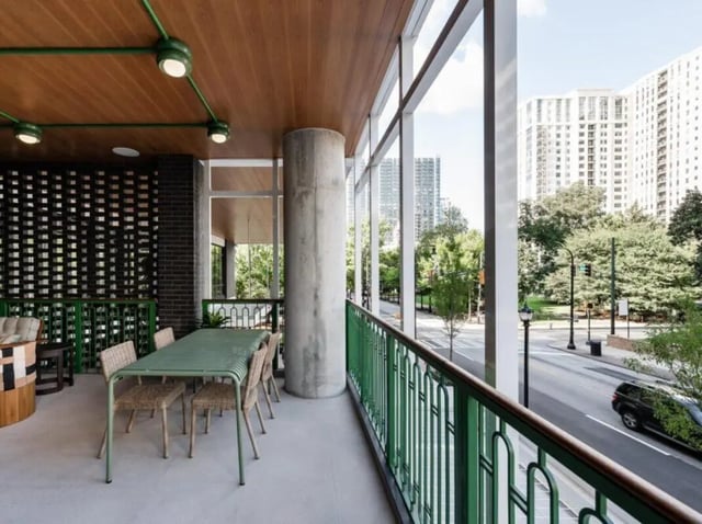 Green dining table chairs concrete column balcony exterior at Rambler Atlanta Apartments in Atlanta Student Accommodation