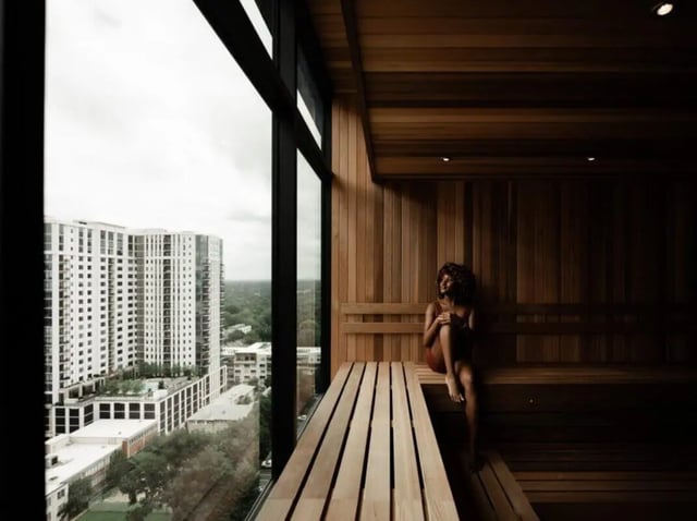 Woman sitting on wooden bench overlooking city sauna at Rambler Atlanta Apartments in Atlanta Student Accommodation