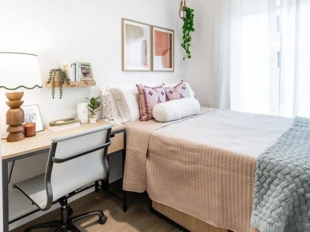Desk chair bed with pillows artwork and plants bedroom at Rambler Atlanta Apartments in Atlanta Student Accommodation