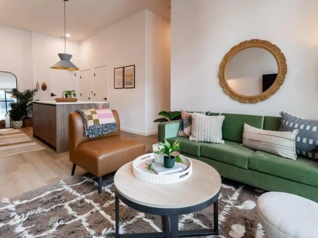 Green sofa patterned rug coffee table living room at Rambler Atlanta Apartments in Atlanta Student Accommodation
