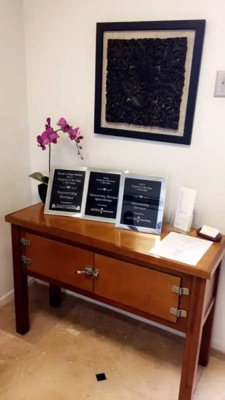 Awards on desk with orchid and artwork entryway decor at University Terrace Apartments in State College Student Accommodation