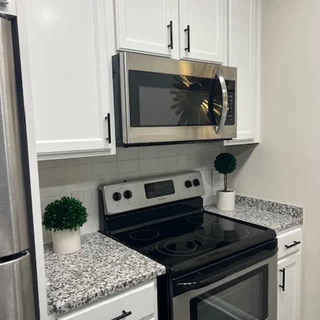 Stainless steel microwave stove white cabinets granite kitchen at Millennium One Apartments in Charlotte Student Accommodation