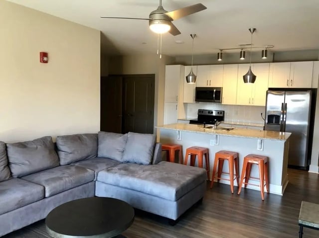 Grey sectional sofa kitchen island orange stools living room kitchen at Plaza One 89 in Clemson Student Accommodation
