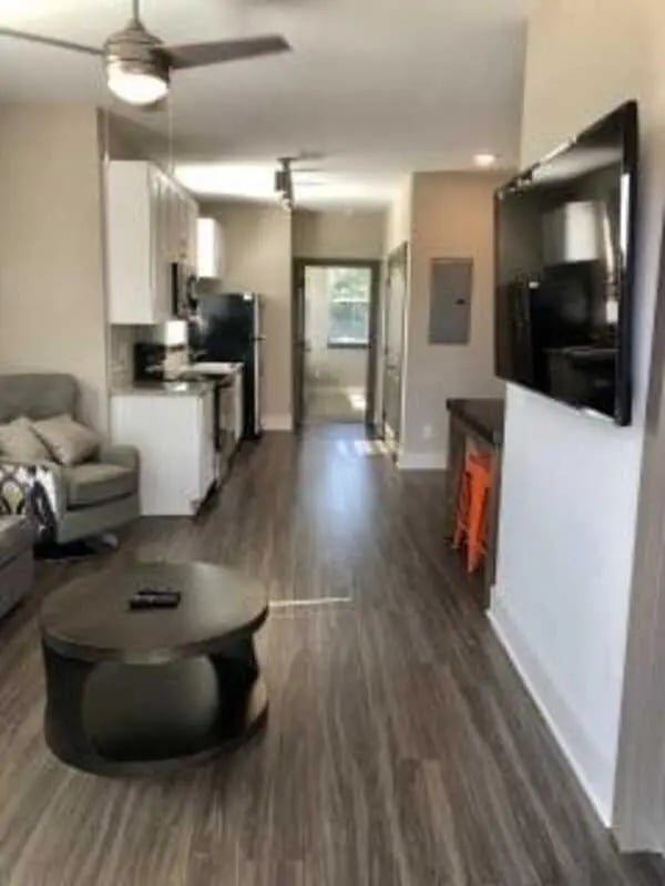Sofa coffee table kitchen living room and hallway at Plaza One 89 in Clemson Student Accommodation