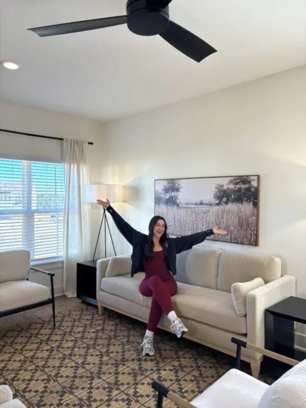 Woman on sofa ceiling fan patterned rug living room at Maverick Hills in Central Student Accommodation