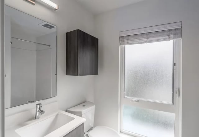Sink toilet mirror cabinet frosted window bathroom at Montclair Apartments in Seattle Student Accommodation