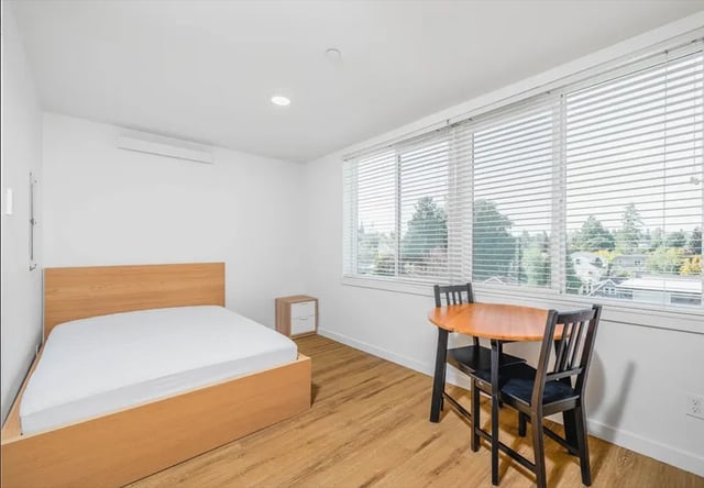 Bed nightstand table chairs windows bedroom at Montclair Apartments in Seattle Student Accommodation