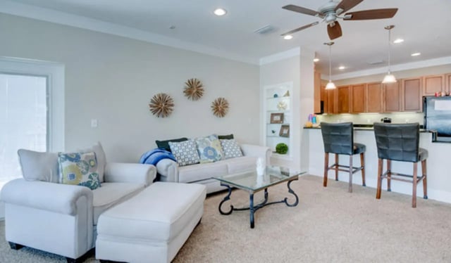 White sectional sofa glass table kitchen bar stools living area at Greystone Luxury Apartments in Gainesville Student Accommodation