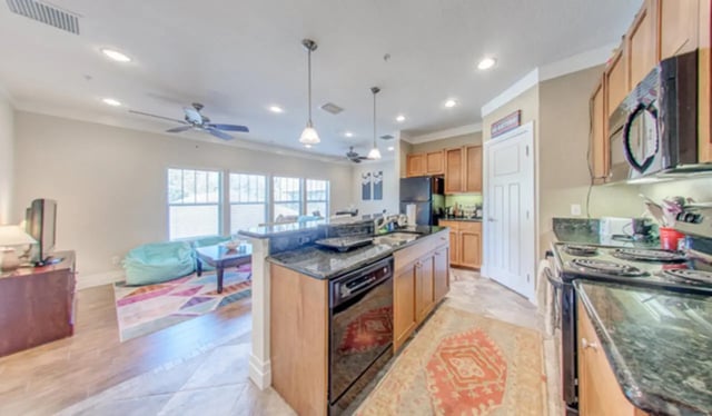 Island kitchen with black countertops and wood cabinets kitchen at Greystone Luxury Apartments in Gainesville Student Accommodation