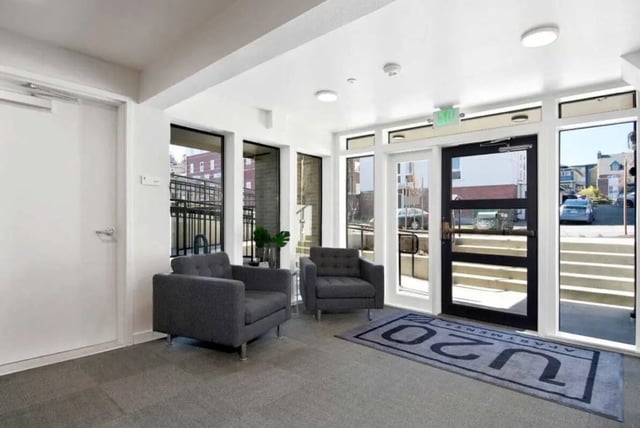 Two gray armchairs near glass doors entrance area at U20 Apartments in Seattle Student Accommodation