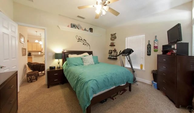 Bed treadmill dresser TV bedroom at Stratford Court Luxury Apartments in Gainesville Student Accommodation