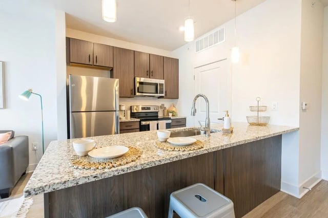 Stainless steel refrigerator granite counter and stools kitchen at The Eden Apartments in Cincinnati Student Accommodation
