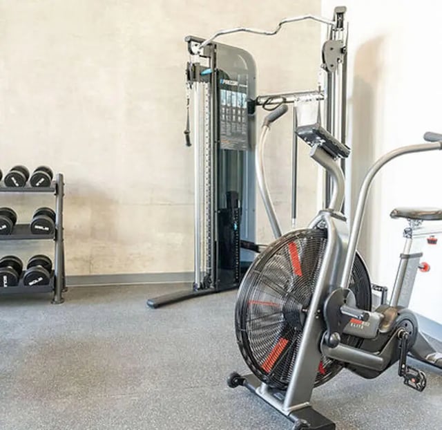 Dumbbell rack air bike cable machine gym area at Aquatic at U in Berkeley Student Accommodation