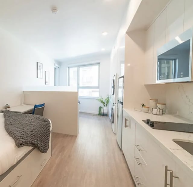 Bed desk chair and modern kitchen living room at Aquatic at U in Berkeley Student Accommodation