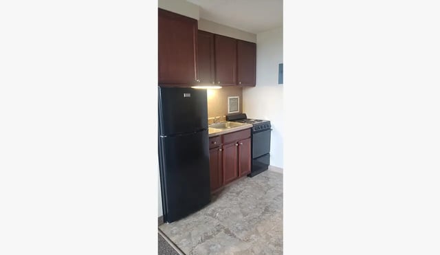 Black refrigerator sink stove brown cabinets kitchen at 100 Chenango Place in Binghamton Student Accommodation