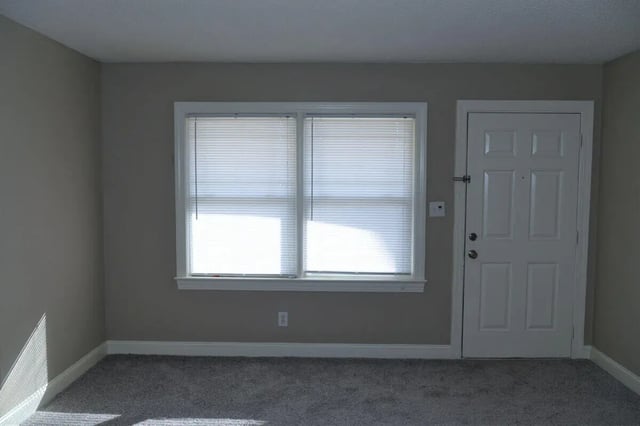 Empty room with carpet blinds and door living room at Campus Walk at ECU in Greenville Student Accommodation