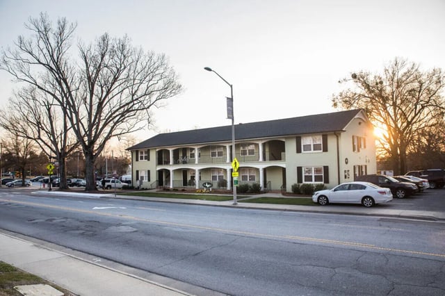 Light green building balconies parking lot cars exterior at Campus Walk at ECU in Greenville Student Accommodation