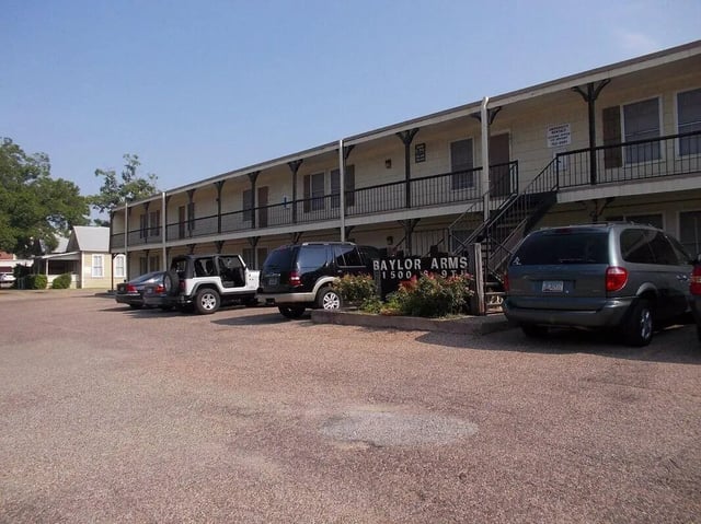 Apartment building with cars parked exterior at Baylor Arms in Waco Student Accommodation