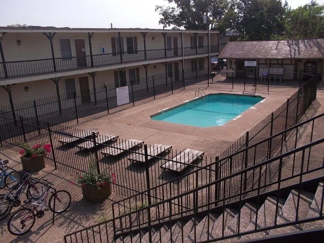 Apartment building pool with lounge chairs exterior at Baylor Arms in Waco Student Accommodation