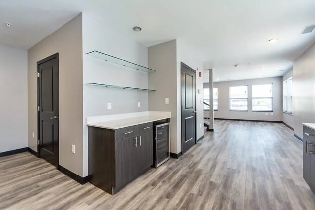 Dark cabinets wine fridge glass shelves living area at CitySide By Alexa in Bloomington Student Accommodation