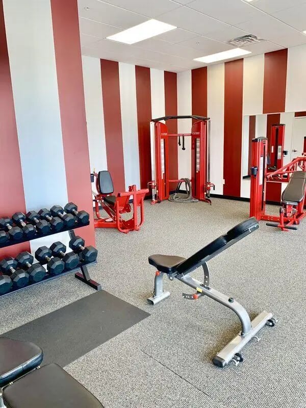 Dumbbells exercise machines and benches gymnasium area at CitySide By Alexa in Bloomington Student Accommodation