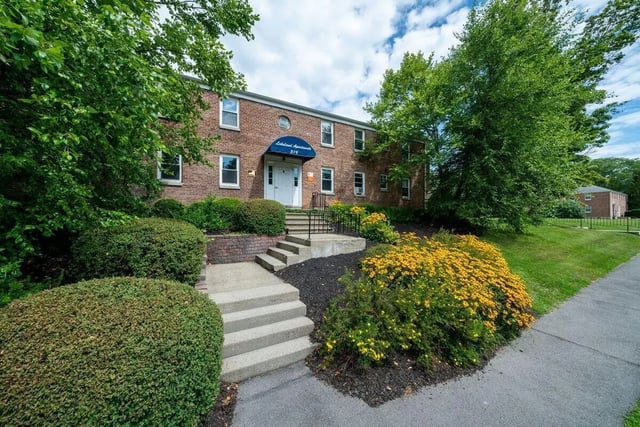 Brick building entrance with stairs and yellow flowers exterior at 407 College Ave in Ithaca Student Accommodation