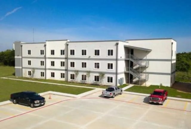 Apartment building with cars in parking lot exterior at 625 at Prairie View Apartments in Prairie View Student Accommodation