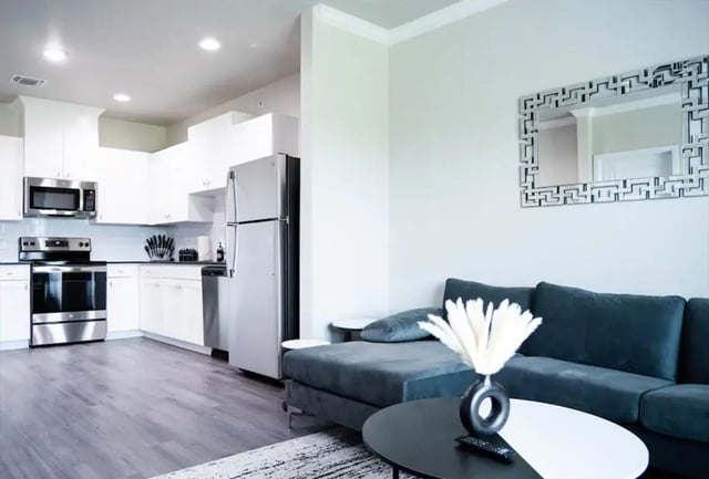 Kitchen with stainless steel appliances and living area living room at 625 at Prairie View Apartments in Prairie View Student Accommodation