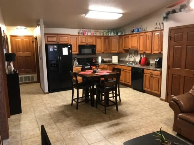 Wooden cabinets black refrigerator square dining table kitchen at Clarks Landing Apartments in Vermillion Student Accommodation