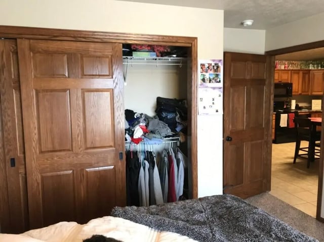 Closet with hanging clothes and clutter kitchen visible Bedroom at Clarks Landing Apartments in Vermillion Student Accommodation
