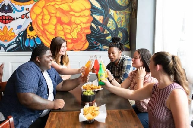 Friends toasting drinks at table with guacamole living room at Campus Apartments Philadelphia in Philadelphia Student Accommodation