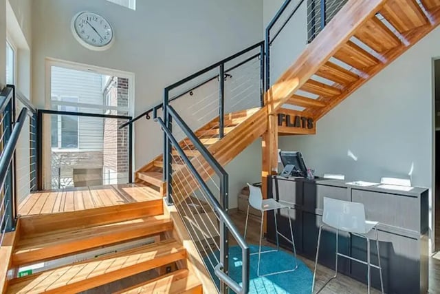 Wooden stairs with metal railing and reception area. at Alpine Flats (NOW UNIVERSITY LANDING) in Logan Student Accommodation