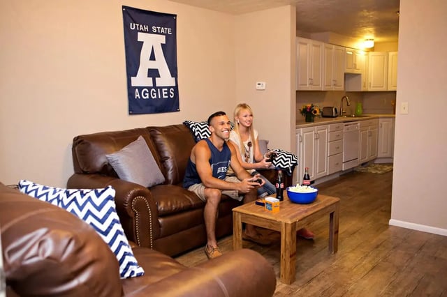 Two students play video games in a living room. at Alpine Flats (NOW UNIVERSITY LANDING) in Logan Student Accommodation