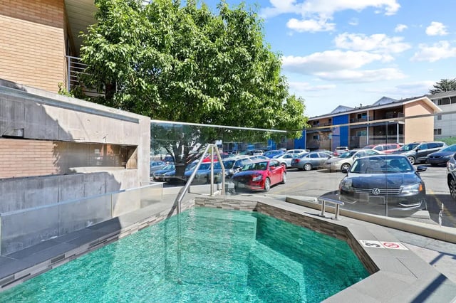 Pool with cars and building exterior at Alpine Flats (NOW UNIVERSITY LANDING) in Logan Student Accommodation