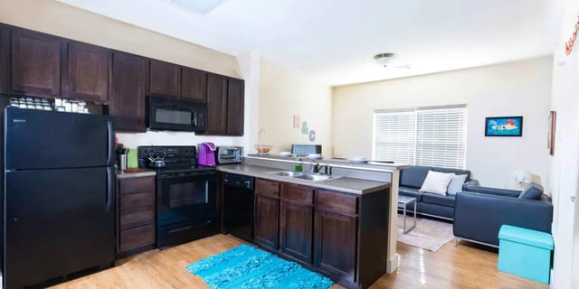 Black refrigerator stove microwave dark cabinets kitchen living room at Beacon Commons in Springfield Student Accommodation