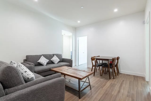 Grey sectional sofa wooden coffee table dining table living area at 1025 Berendo Villas in Los Angeles Student Accommodation
