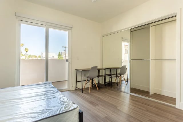Mattress tables chairs mirrored closet bedroom at 1025 Berendo Villas in Los Angeles Student Accommodation
